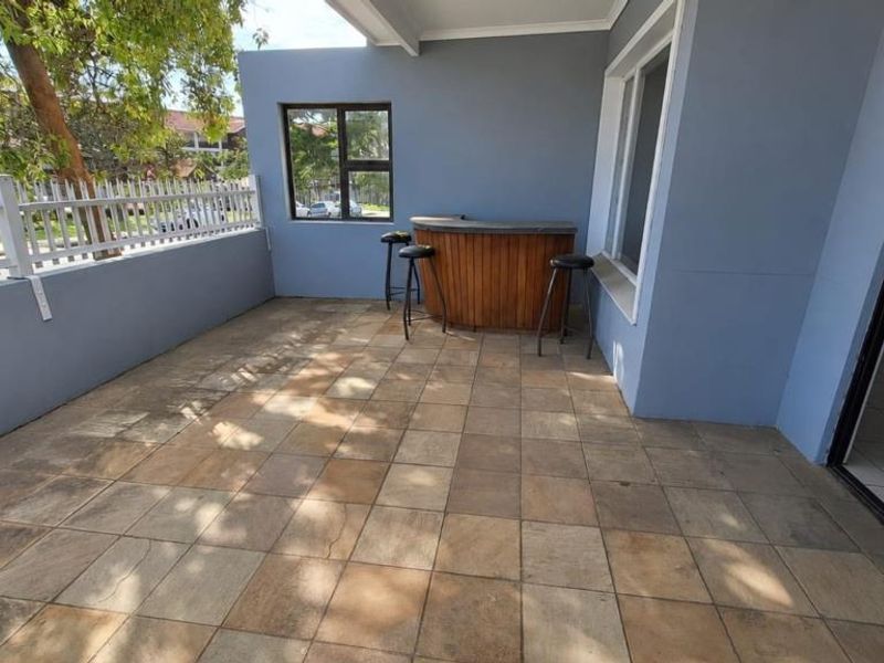 A covered patio area featuring tiled flooring, a built-in bar counter, and direct access to the interior through a sliding glass door.
