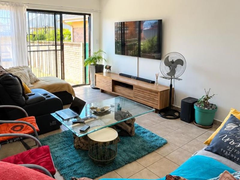 A comfortable living room featuring tiled flooring and a sliding glass door that provides access to the outdoor area.