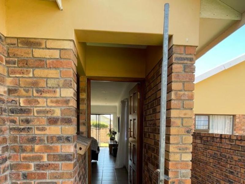 Entrance area of a townhouse featuring face brick construction, a timber front door, and tiled flooring leading into the interior living space.
