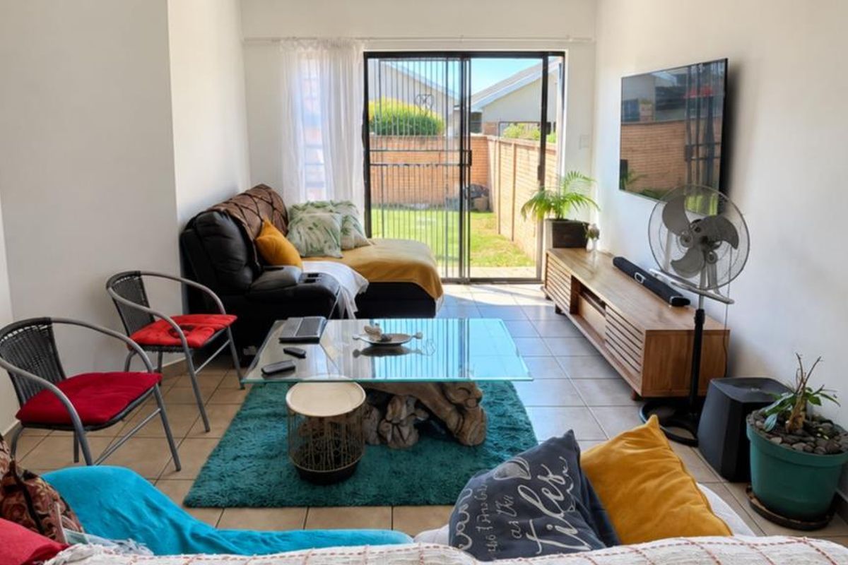A bright living room featuring tiled flooring and a large sliding glass door that provides direct access to the rear garden area.