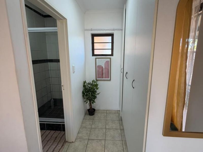 A functional hallway featuring built-in storage cupboards, tiled flooring, and direct access to an adjacent bathroom.