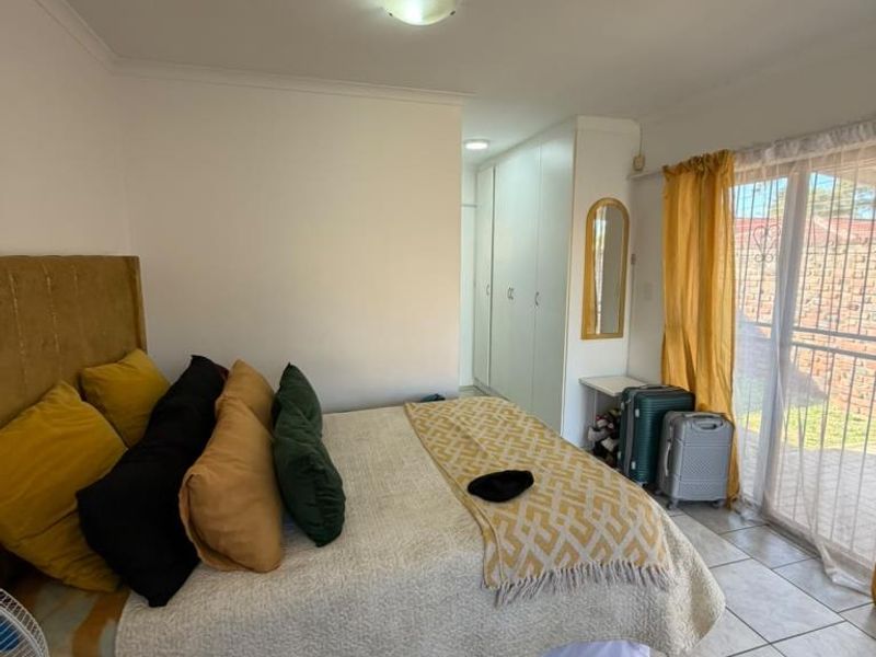 A bedroom featuring built-in cupboards, tiled flooring, and a sliding glass door providing access to the exterior.