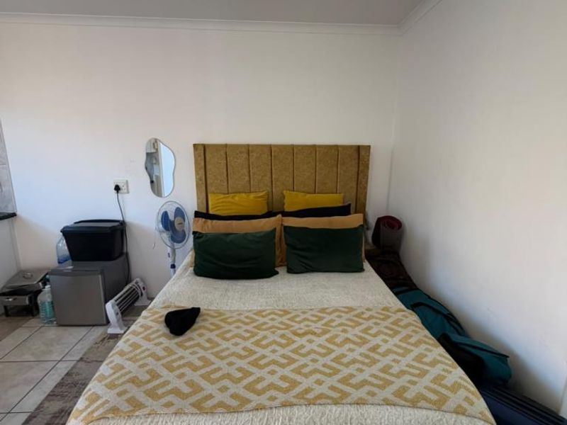 A functional bedroom featuring tiled flooring and a central ceiling light fixture, providing a clean and neutral space for rest.