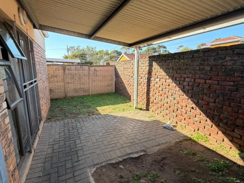 A covered outdoor patio area featuring brick boundary walls and paved flooring, offering a private space for outdoor relaxation.