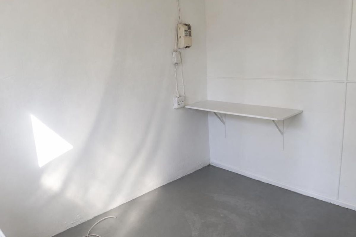 A small, empty utility space featuring a wall-mounted shelf, exposed electrical wiring, and a prepaid electricity meter.