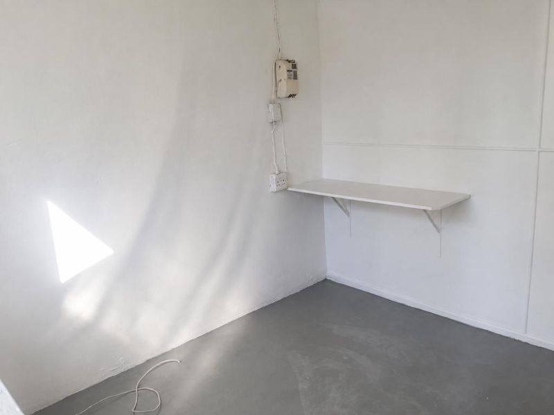 A small, empty utility space featuring a wall-mounted shelf, exposed electrical wiring, and a prepaid electricity meter.