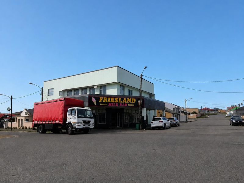 Street view of a commercial building facade featuring Friesland Milk Bar signage, situated on a corner lot with street access.
