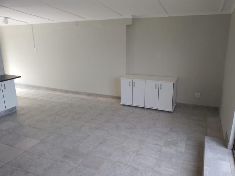 An open-plan living area featuring neutral tiled flooring and built-in cabinetry, offering a clean and versatile space ready for personalization.
