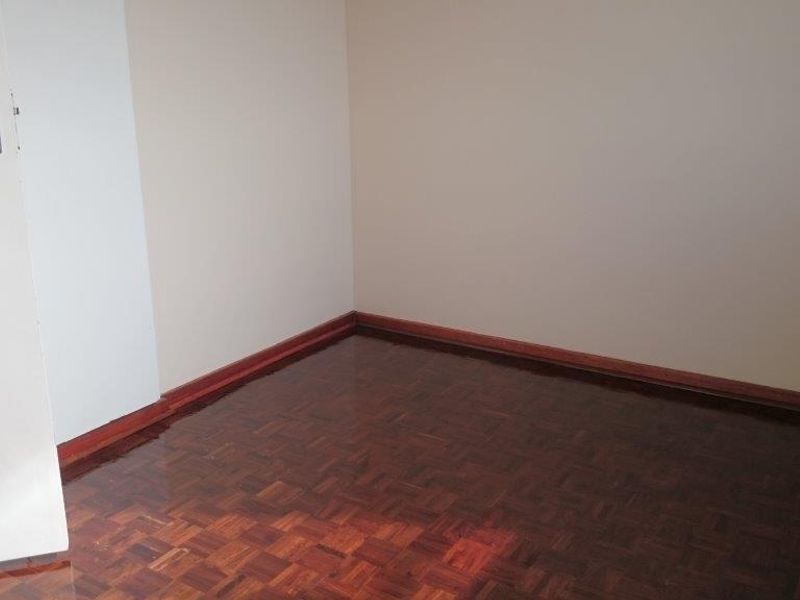 An empty bedroom featuring polished parquet flooring and timber skirting boards, providing a clean and neutral space ready for personalization.