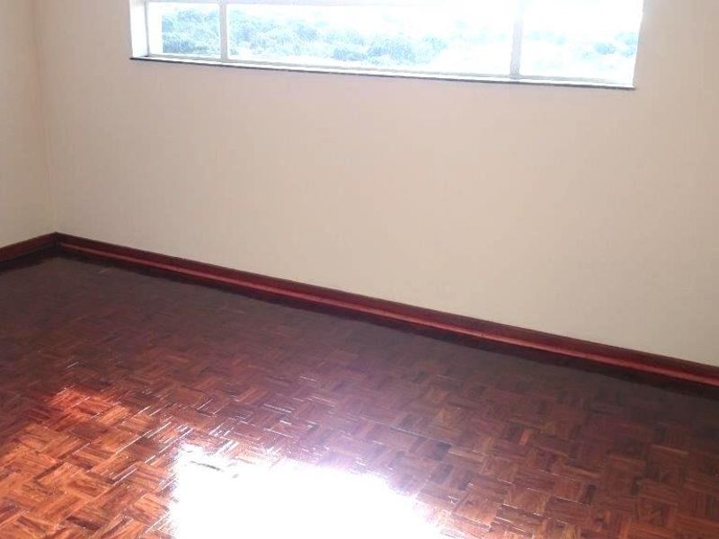 An empty bedroom featuring polished parquet flooring and timber skirting boards, offering a clean and neutral space ready for personalization.