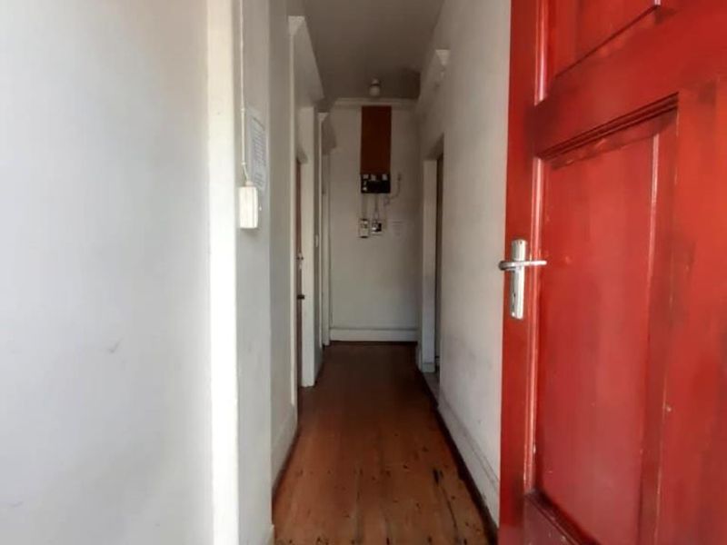 A functional hallway featuring a tiled entrance transition, timber flooring, and a visible electrical distribution board.