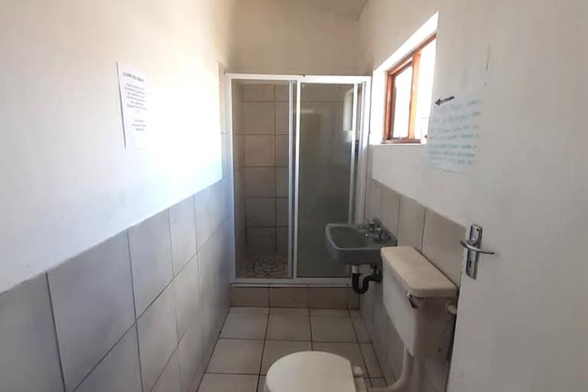 A functional bathroom featuring a shower enclosure, wall-mounted basin, and toilet with tiled finishes throughout.