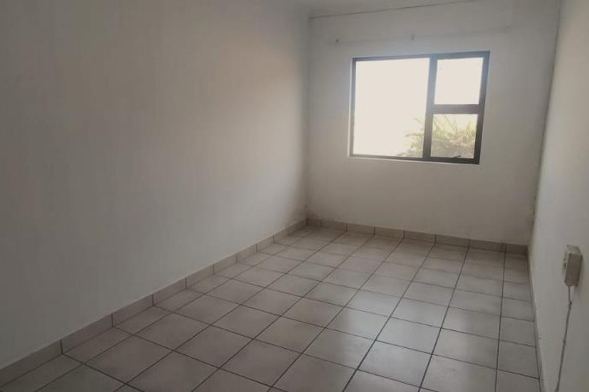 A vacant bedroom featuring neutral tiled flooring and a large window, providing a blank canvas for interior design and personalization.