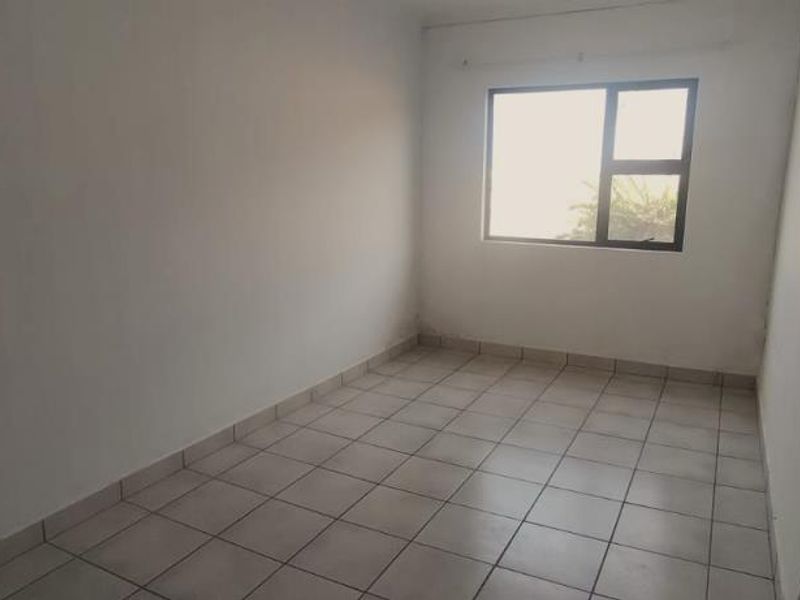 A vacant bedroom featuring neutral tiled flooring and a large window, providing a blank canvas for interior design and personalization.