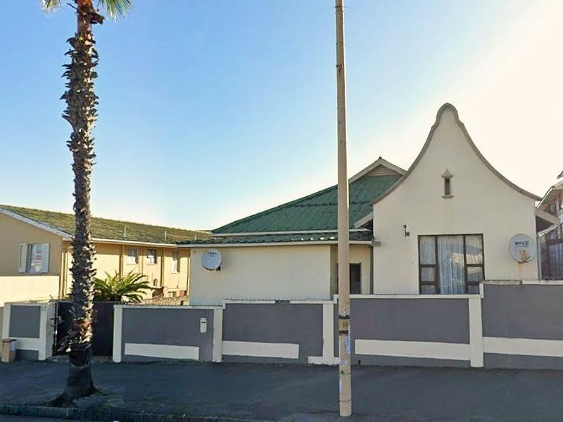 Front exterior view of the property featuring a boundary wall, gated entrance, and pitched roof architecture.