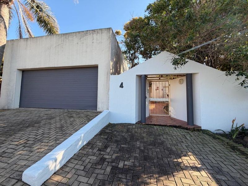 Front exterior view of the property featuring a double garage, paved driveway, and a private pedestrian entrance gate.