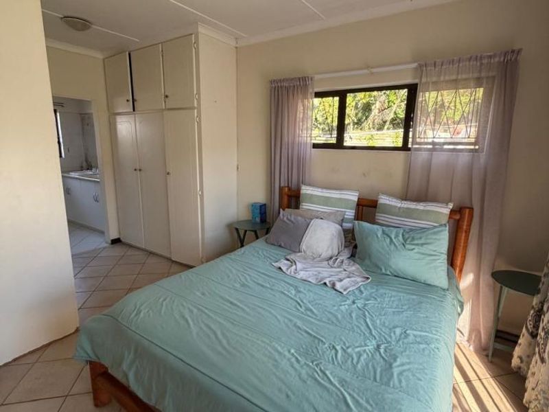 Bedroom featuring built-in cupboards, tiled flooring, and a ceiling fan, with direct access to an adjacent room.