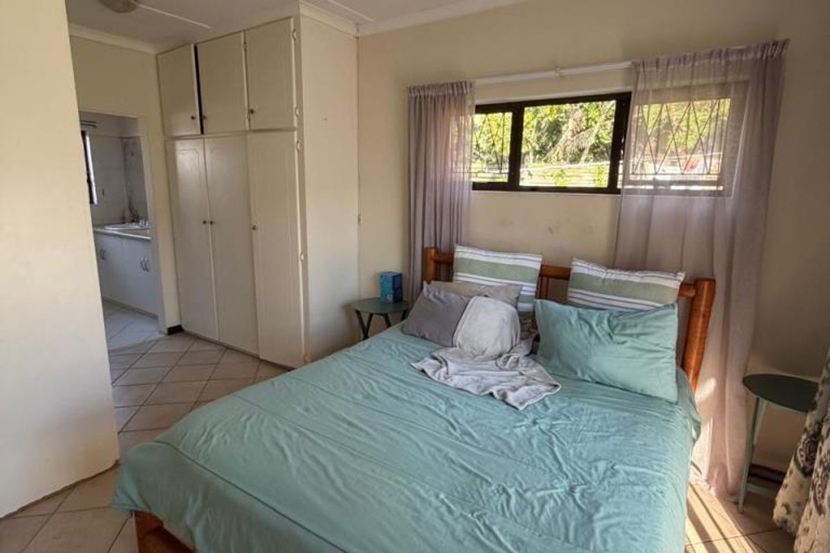Bedroom featuring built-in cupboards, tiled flooring, and a ceiling fan, with direct access to an adjacent room.