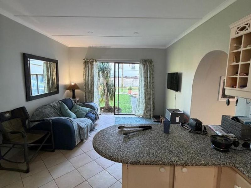 Open-plan living and kitchen area featuring tiled flooring, granite countertops, and a sliding glass door providing direct access to the rear garden.