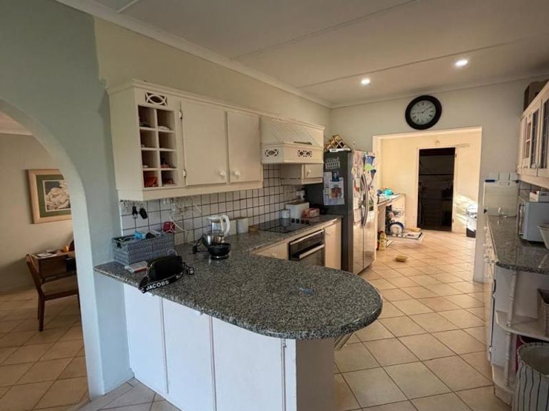 Kitchen featuring granite countertops, built-in oven, hob, and extractor fan, with an open-plan layout leading to adjacent living areas.