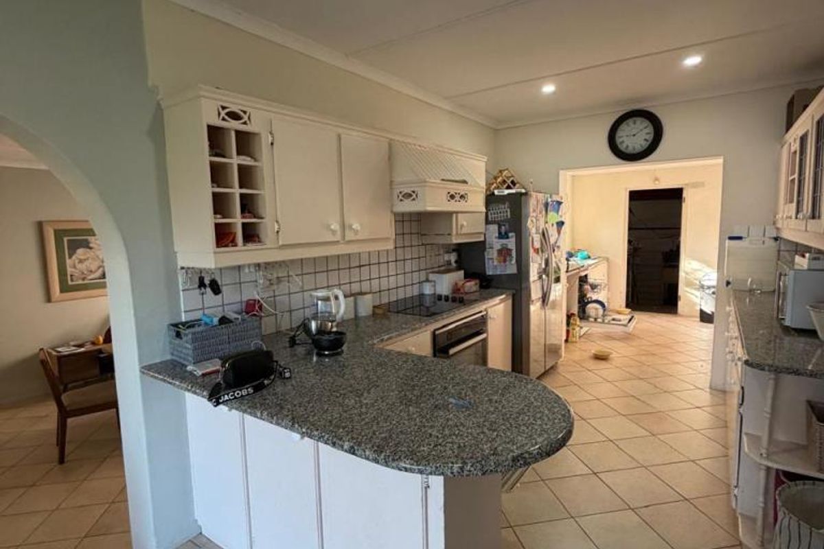 Kitchen featuring granite countertops, built-in oven, hob, and extractor fan, with an open-plan layout leading to adjacent living areas.