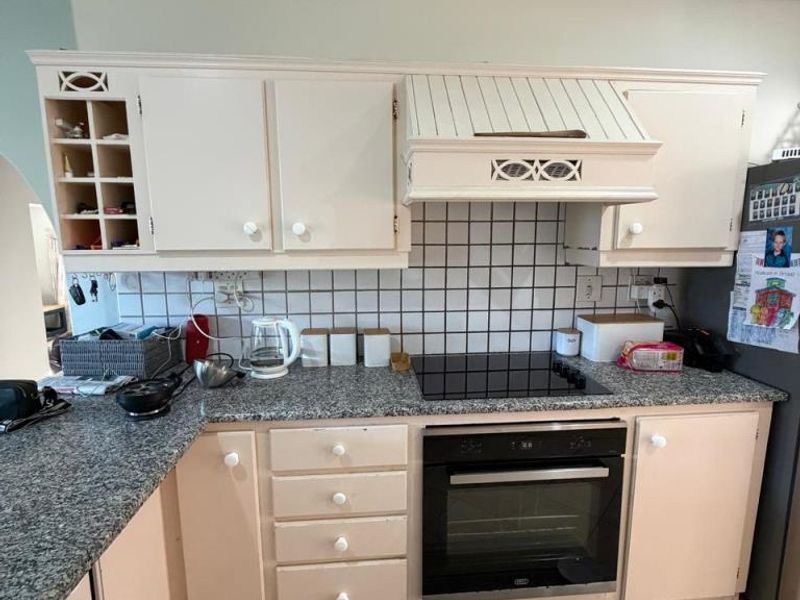 A functional kitchen featuring built-in cabinetry, granite countertops, a tiled backsplash, and integrated cooking appliances including an oven and hob.