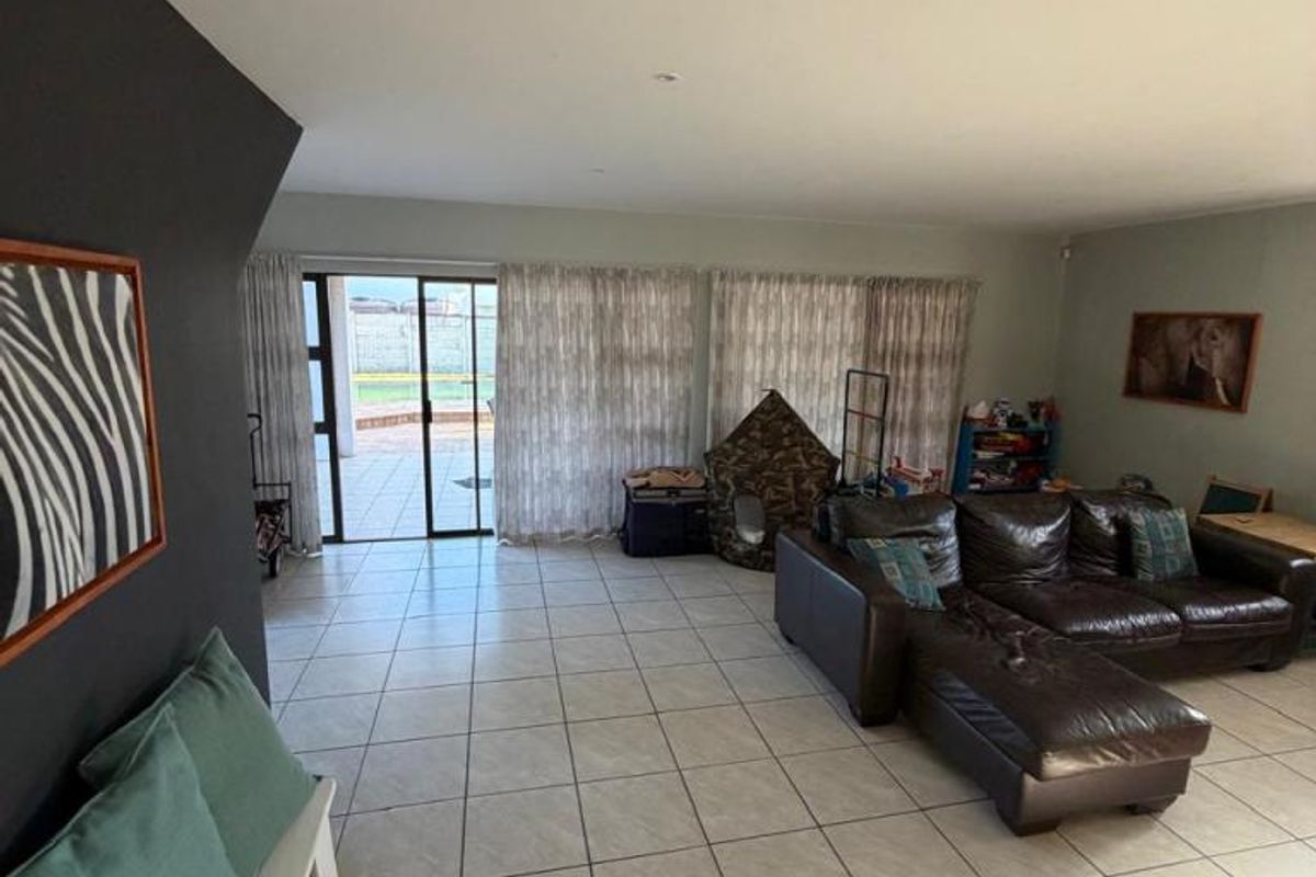 Spacious living room featuring neutral tiled flooring, recessed lighting, and large sliding glass doors providing direct access to the outdoor patio area.