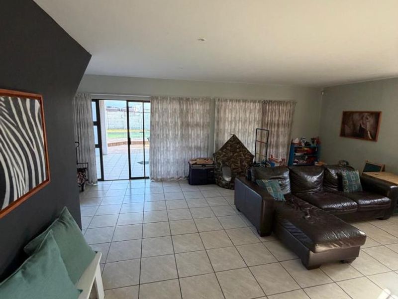 Spacious living room featuring neutral tiled flooring, recessed lighting, and large sliding glass doors providing direct access to the outdoor patio area.