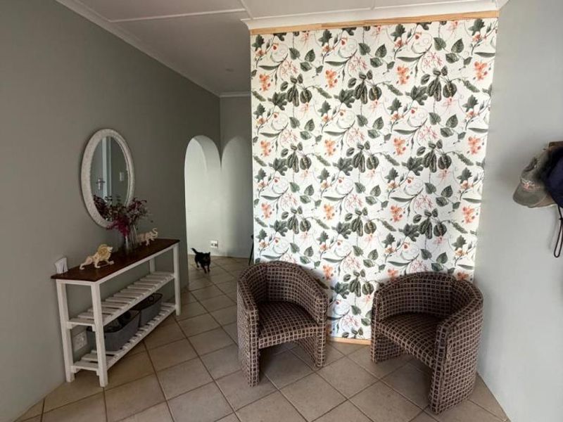 An entry area featuring ceramic floor tiles, a decorative wallpapered feature wall, and an arched doorway leading to the interior of the home.