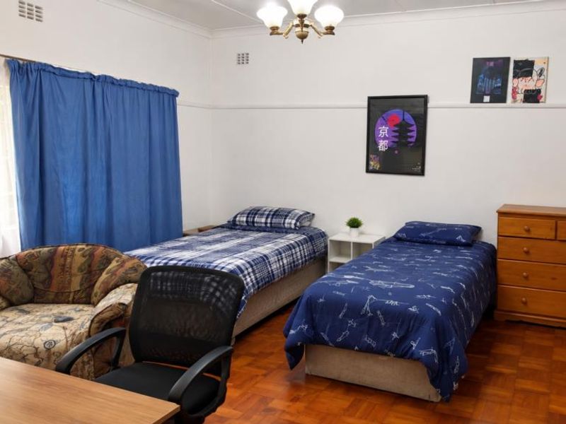 A spacious bedroom featuring classic parquet flooring, a ceiling rose, and a picture rail, offering a functional layout with natural light.