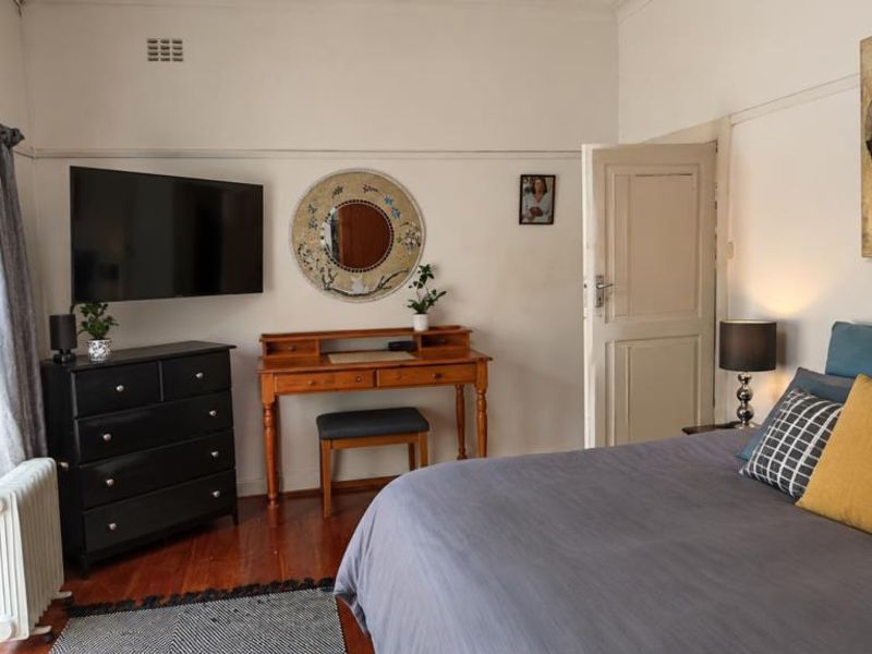 A well-maintained bedroom featuring hardwood flooring, a classic picture rail, and a sliding glass door providing access to the exterior.
