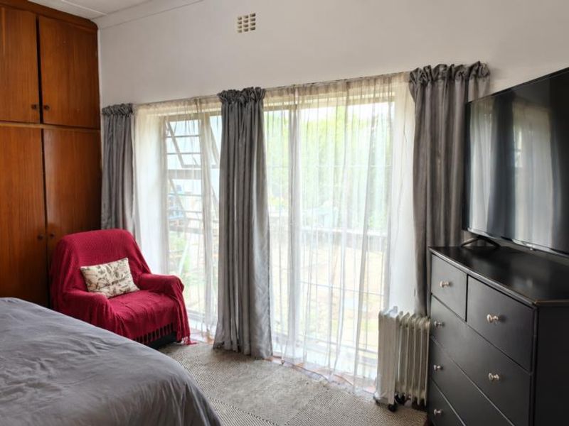 A bedroom featuring extensive built-in wooden cabinetry and a large sliding glass door providing natural light and garden access.