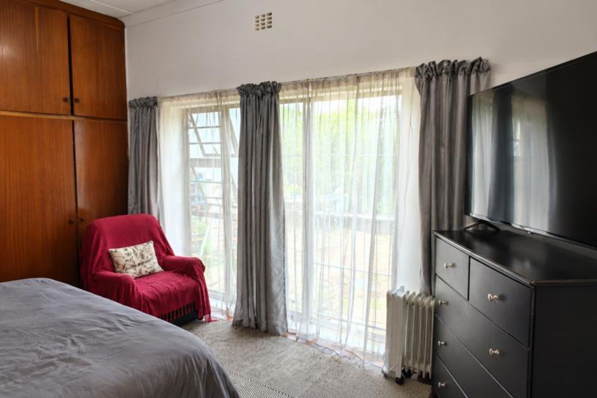 A bedroom featuring extensive built-in wooden cabinetry and a large sliding glass door providing natural light and garden access.