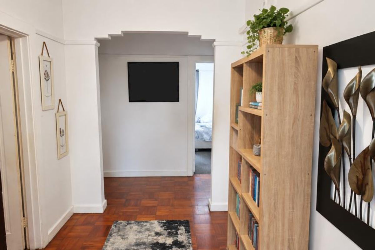 A bright hallway featuring classic parquet flooring and a distinctive stepped archway leading to adjacent rooms.