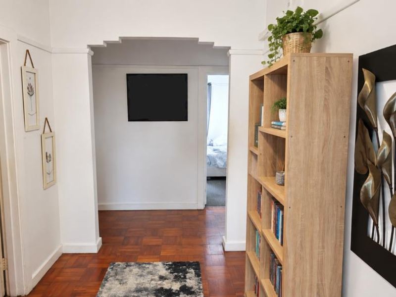 A bright hallway featuring classic parquet flooring and a distinctive stepped archway leading to adjacent rooms.