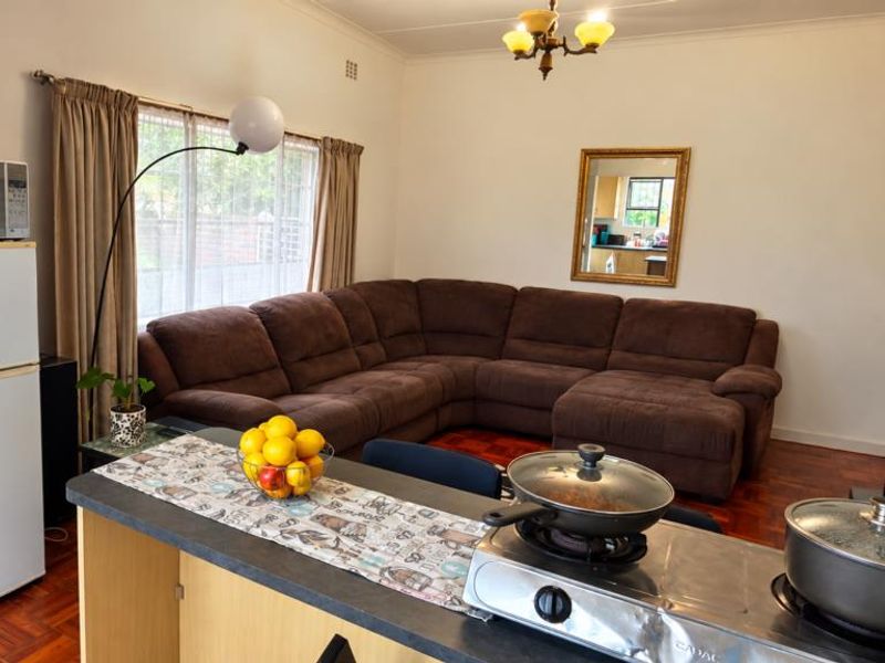 Open-plan living area featuring parquet flooring and a functional breakfast counter, creating a combined space for dining and relaxation.