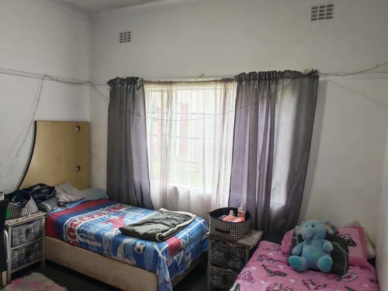 A bedroom featuring a large window with natural light, coving, and a picture rail. The room requires cosmetic updates to the wall finishes.