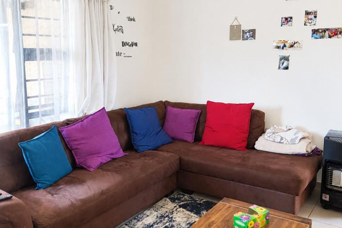 A comfortable living room area featuring tiled flooring and natural light from the window, providing a functional space for relaxation.