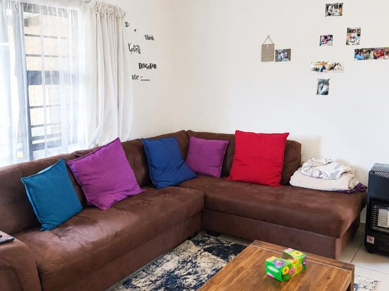 A comfortable living room area featuring tiled flooring and natural light from the window, providing a functional space for relaxation.
