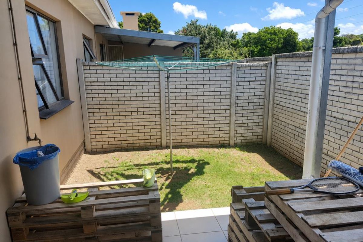 A private rear courtyard featuring a tiled patio area, a small lawn, and brick boundary walls, providing a functional outdoor space.