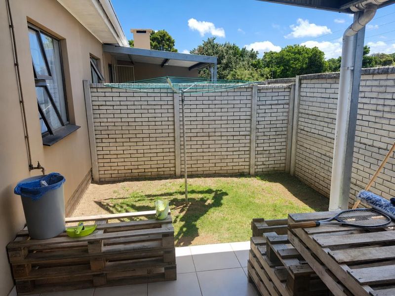 A private rear courtyard featuring a tiled patio area, a small lawn, and brick boundary walls, providing a functional outdoor space.