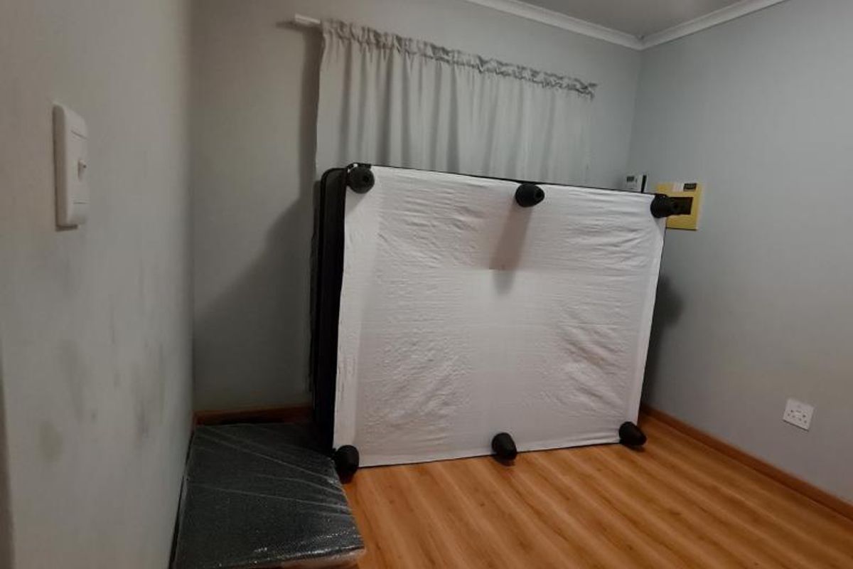 A vacant bedroom featuring laminate flooring, neutral wall tones, and a ceiling light fixture, ready for new occupants to personalize the space.