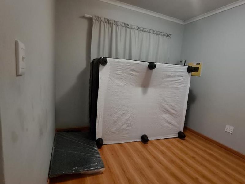 A vacant bedroom featuring laminate flooring, neutral wall tones, and a ceiling light fixture, ready for new occupants to personalize the space.