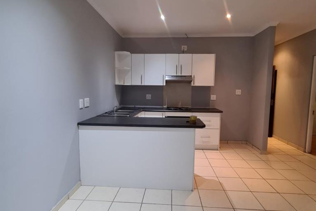 A clean, modern kitchen featuring white cabinetry, dark countertops, and tiled flooring, offering a functional and well-lit space for culinary activities.