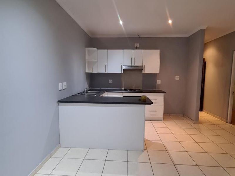 A clean, modern kitchen featuring white cabinetry, dark countertops, and tiled flooring, offering a functional and well-lit space for culinary activities.