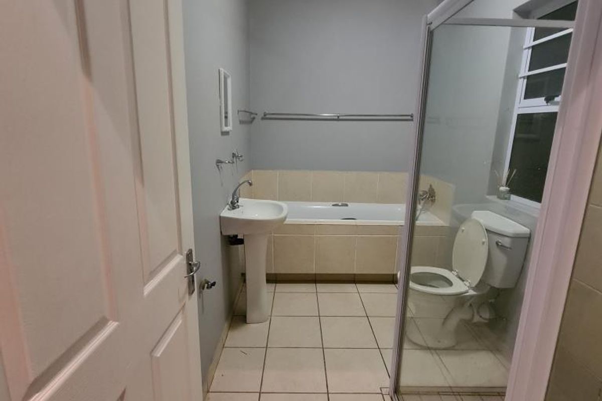 A functional bathroom featuring a pedestal basin, built-in bathtub, separate shower enclosure, and tiled flooring.