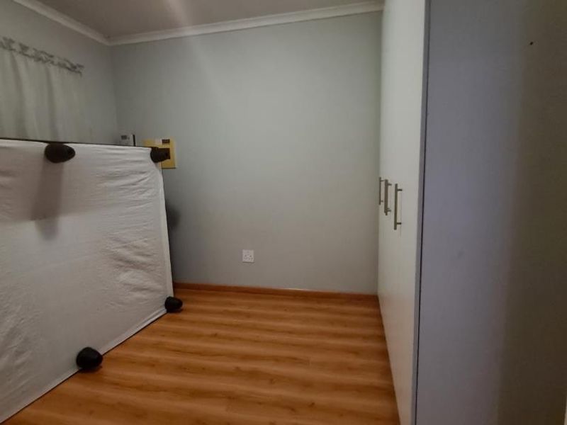 A bedroom featuring laminate flooring and built-in cupboards, providing a clean and functional space ready for personalization.