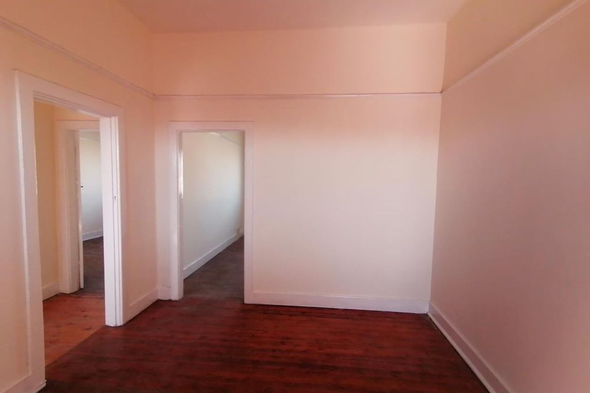 An empty living room featuring original hardwood flooring and classic picture rails, offering a blank canvas for renovation or interior design.