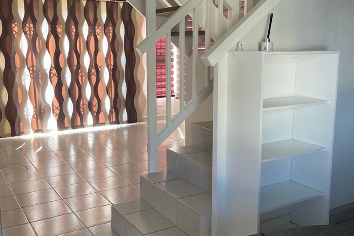 Open plan living area featuring a tiled staircase with wooden treads, built-in shelving, and a granite countertop, creating a functional and connected space.