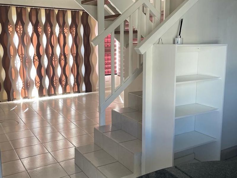 Open plan living area featuring a tiled staircase with wooden treads, built-in shelving, and a granite countertop, creating a functional and connected space.